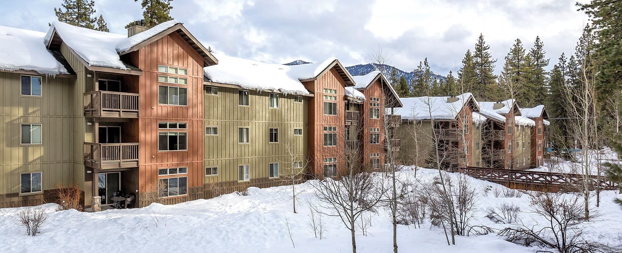 Eine mehrstöckige Lodge mit Holzfassade, Balkonen und verschneiter Landschaft.