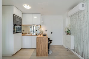 A modern kitchen with built-in appliances, a wooden island, and a white door. - Panorama Coastal Haven (Split)