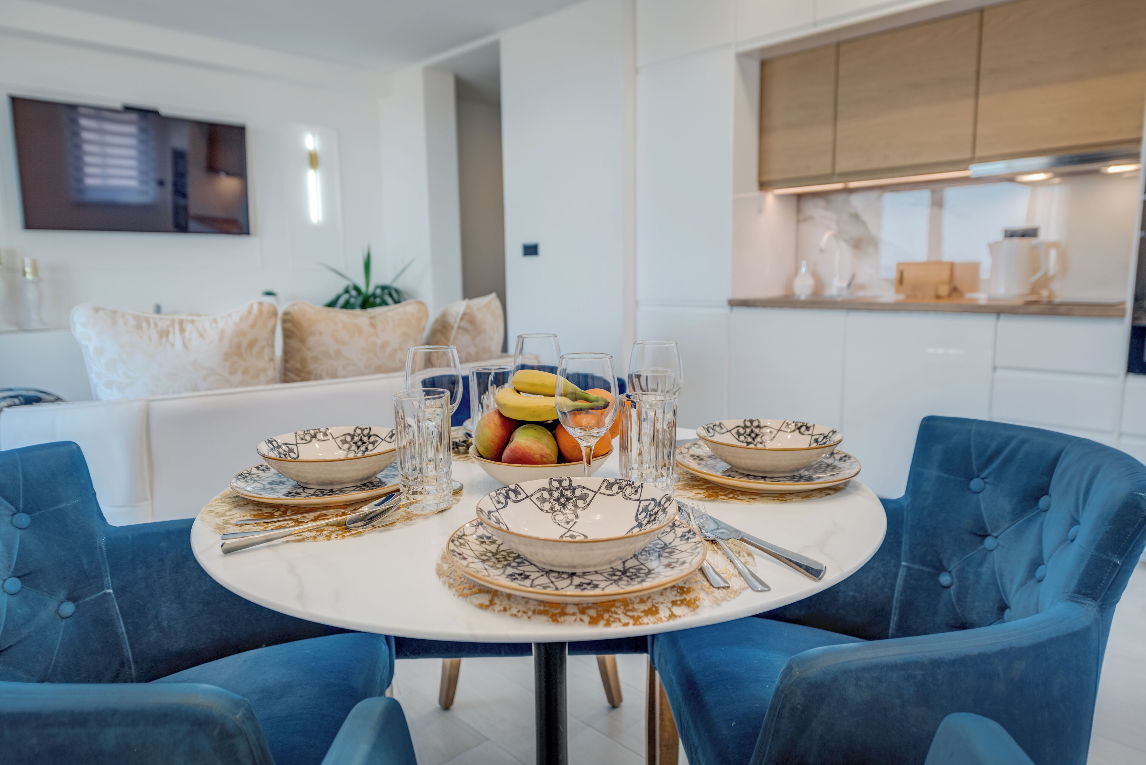 A dining table set with plates, bowls, and cutlery, surrounded by blue upholstered chairs.