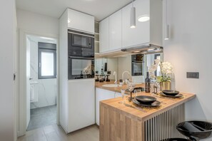 Una cucina moderna con mobili bianchi, un piano di lavoro in legno e un forno integrato.