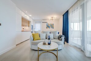 Una sala de estar moderna con un sofá, una mesa de centro y una zona de cocina al fondo.