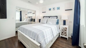 Ein Schlafzimmer mit Bett, Nachttisch, Spiegel und Deckenventilator.
