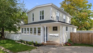 A two-story house with a porch, a sign indicating it's a guest house, and a fenced yard. - ChesterGuestHouse · Charming Chester Classic in Village Core (Chester)