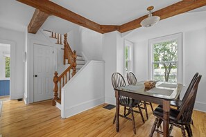 A dining area with a wooden table and chairs, a staircase with wooden railings, and a view through a window. - ChesterGuestHouse · Charming Chester Classic in Village Core (Chester)