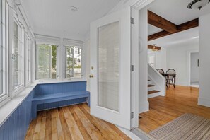 A room with a wooden floor, a bench, a door leading to another room, and a staircase. - ChesterGuestHouse · Charming Chester Classic in Village Core (Chester)