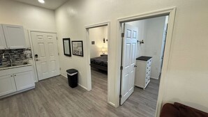 A modern kitchen with white cabinets, a granite countertop, and a black trash can. - Historic King Suite in Upton's Confectionery (Globe)