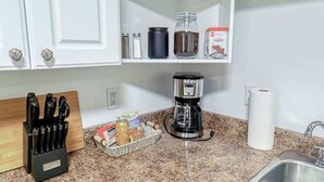 Una cocina con cafetera, cuchillos, especias y un dispensador de toallas de papel.