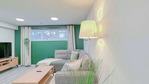 Una sala de estar moderna con sofá, mesa de centro, televisor y lámpara.