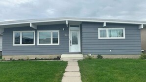 A single-story house with a front door, two windows on the left, and a garage door on the right.