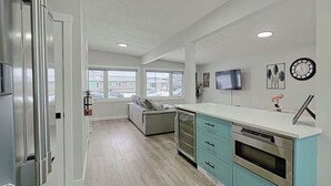 A modern kitchen with a built-in oven, a TV mounted on the wall, and a window providing a view of the outside.