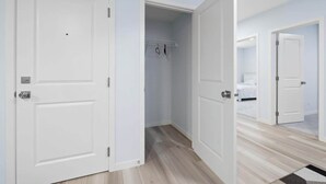 A bedroom with a bed, a closet, and a hallway leading to another room.