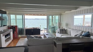 A modern interior with a sofa, a dining table, and a view of the water.
