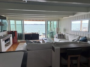 Ein modernes Interieur mit einer Couch, einem Esstisch und Blick auf das Wasser.