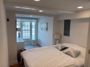 Ein Schlafzimmer mit einem Bett, einem Fenster, einer Lampe und einem Bild an der Wand.