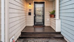 A house entrance with a dark front door, a mailbox, and a potted plant.