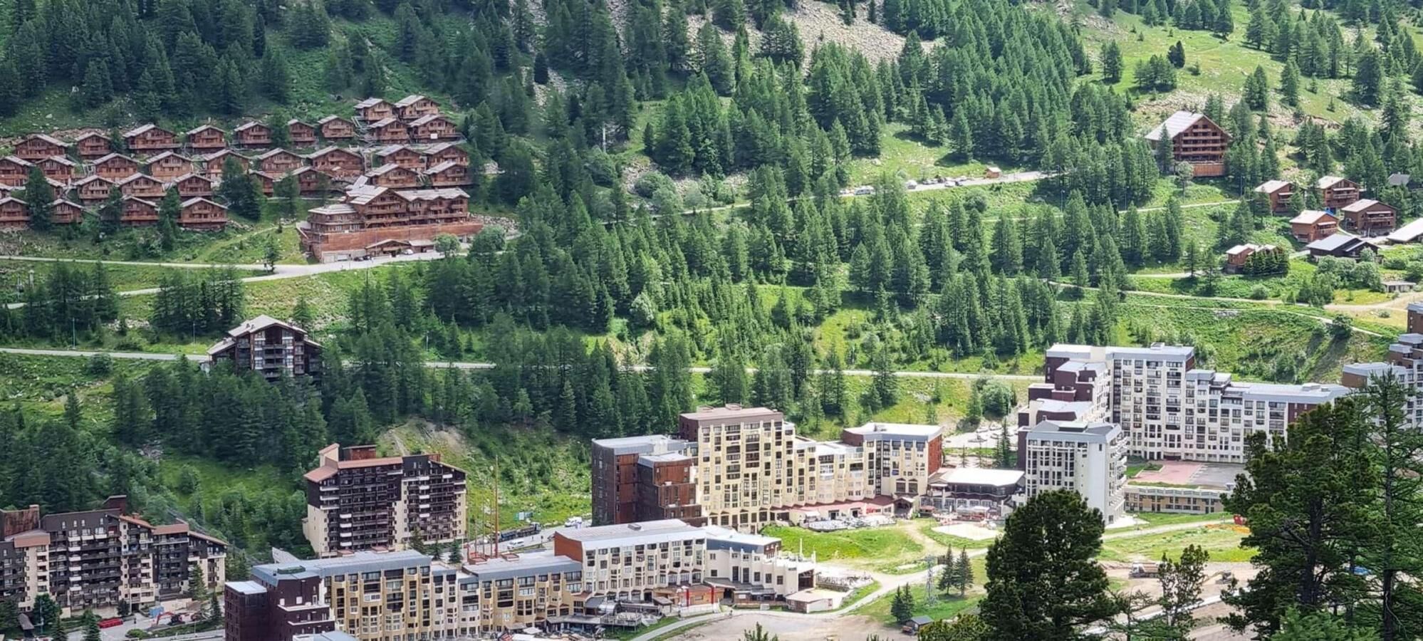A mountainous area with a mix of traditional wooden lodges and modern buildings, surrounded by dense forest.