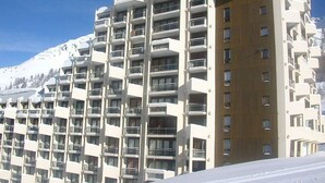 Ett hotell med flera våningar, balkonger, en träfasad och ett snötäckt berg i bakgrunden.