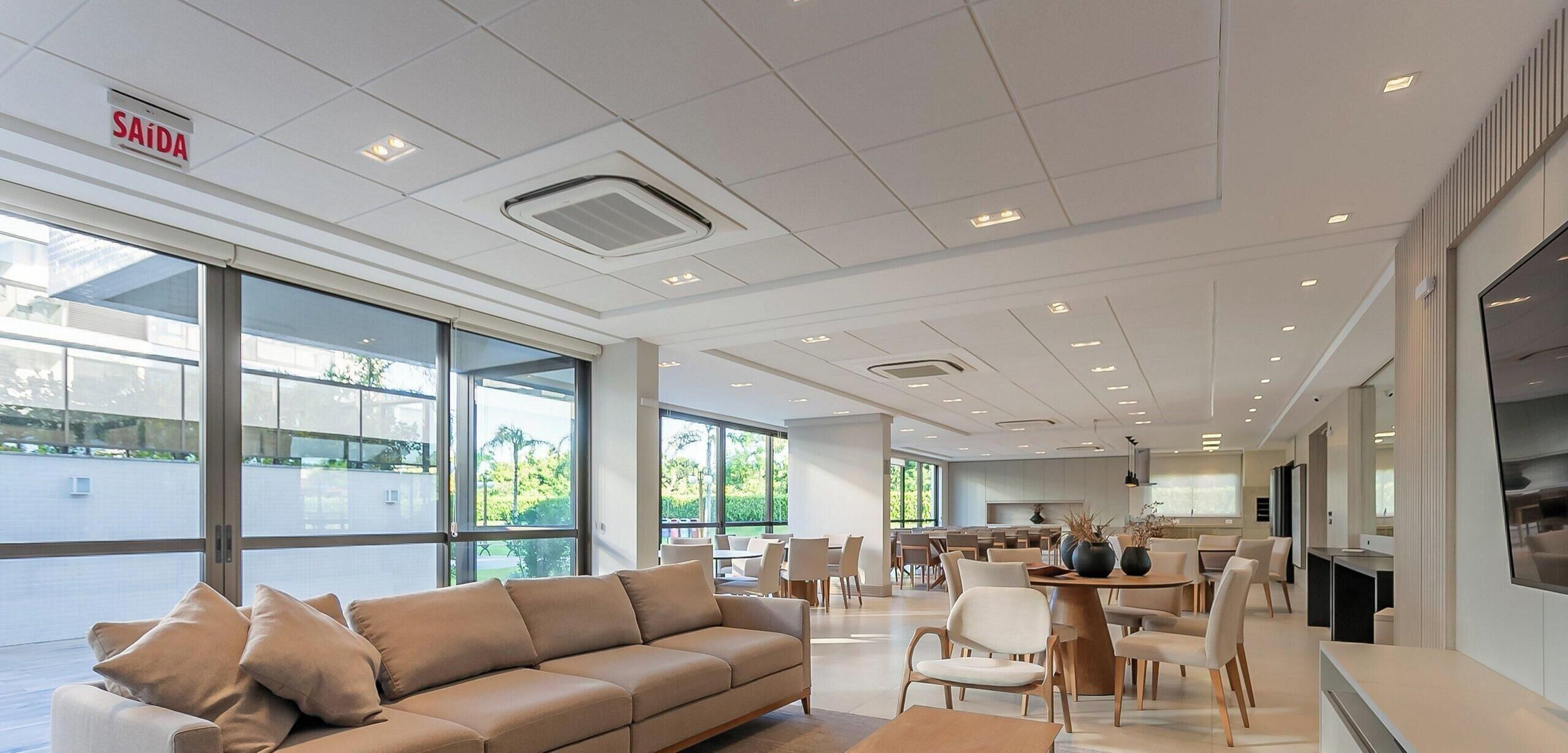 A modern hotel lobby with a sofa, dining area, and large windows.