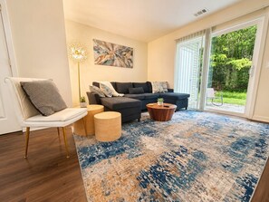 A living room with a sofa, two side tables, a chair, and a large rug.