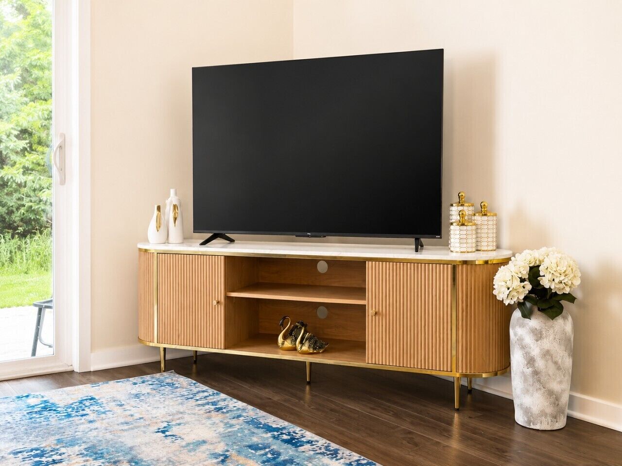 En moderne stue med et fladskærms-tv, en tv-reol i træ og en vase med blomster.
