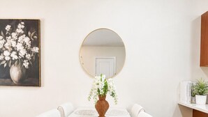 A dining table with a vase of flowers, a mirror above it, and a white wall. - Holiday Village Townhomes – 3883 (Traverse City)