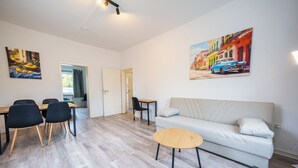 Ein modernes Wohnzimmer mit einer Couch, einem runden Couchtisch und einem Essbereich mit Stühlen und Tisch.