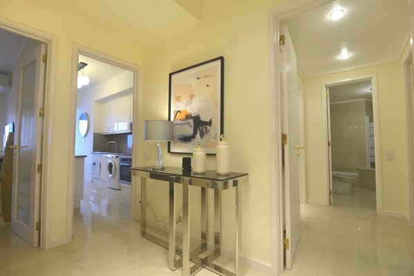 A hallway with a glass console table, a framed picture, and a washing machine in the background. - Luxury Ocean View (Ponta Delgada)