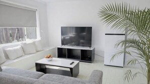 Ett modernt vardagsrum med en soffa, ett soffbord, en tv och ett kylskåp.