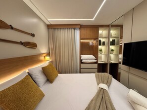 Ein Hotelzimmer mit Bett, Holz-Kopfteil, Nachttischlampen, Fernseher, Kleiderschrank und Spiegel.