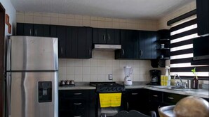 A kitchen with black cabinets, a stainless steel refrigerator, a stove, and a sink. - Casa AMAR-i-LLA - Centrally located and with A/C (Guadalajara)