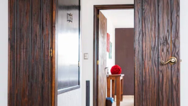 An open wooden door leading to a hallway with a tiled floor and a small table with a red spherical object on it. - Casa AMAR-i-LLA - Centrally located and with A/C (Guadalajara)