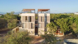 Un edifici modern de dues plantes amb teulada plana, finestres grans i una pèrgola al pis superior.