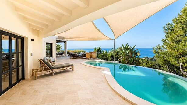 Ein Poolbereich mit Liegestühlen, einer überdachten Sitzgelegenheit und Blick auf den Ozean.