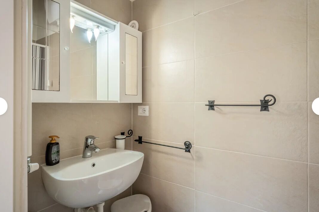 A bathroom with a white sink, a mirror, a towel rack, and a toilet.