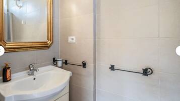 Ein Badezimmer mit einem weißen Waschbecken, einem Spiegel mit goldener Rahmung und einem Handtuchhalter.