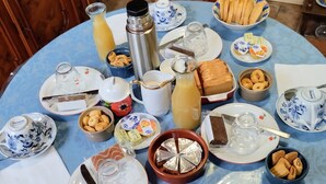 A round table with various breakfast items, including bread, pastries, and a teapot. - CHARMING LUCCA (Lucca)