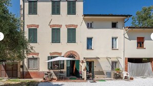 A two-story building with a patio area, a table, and chairs. - CHARMING LUCCA (Lucca)