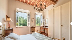 A bedroom with a bed, a desk, a chair, a chandelier, and a wardrobe. - CHARMING LUCCA (Lucca)