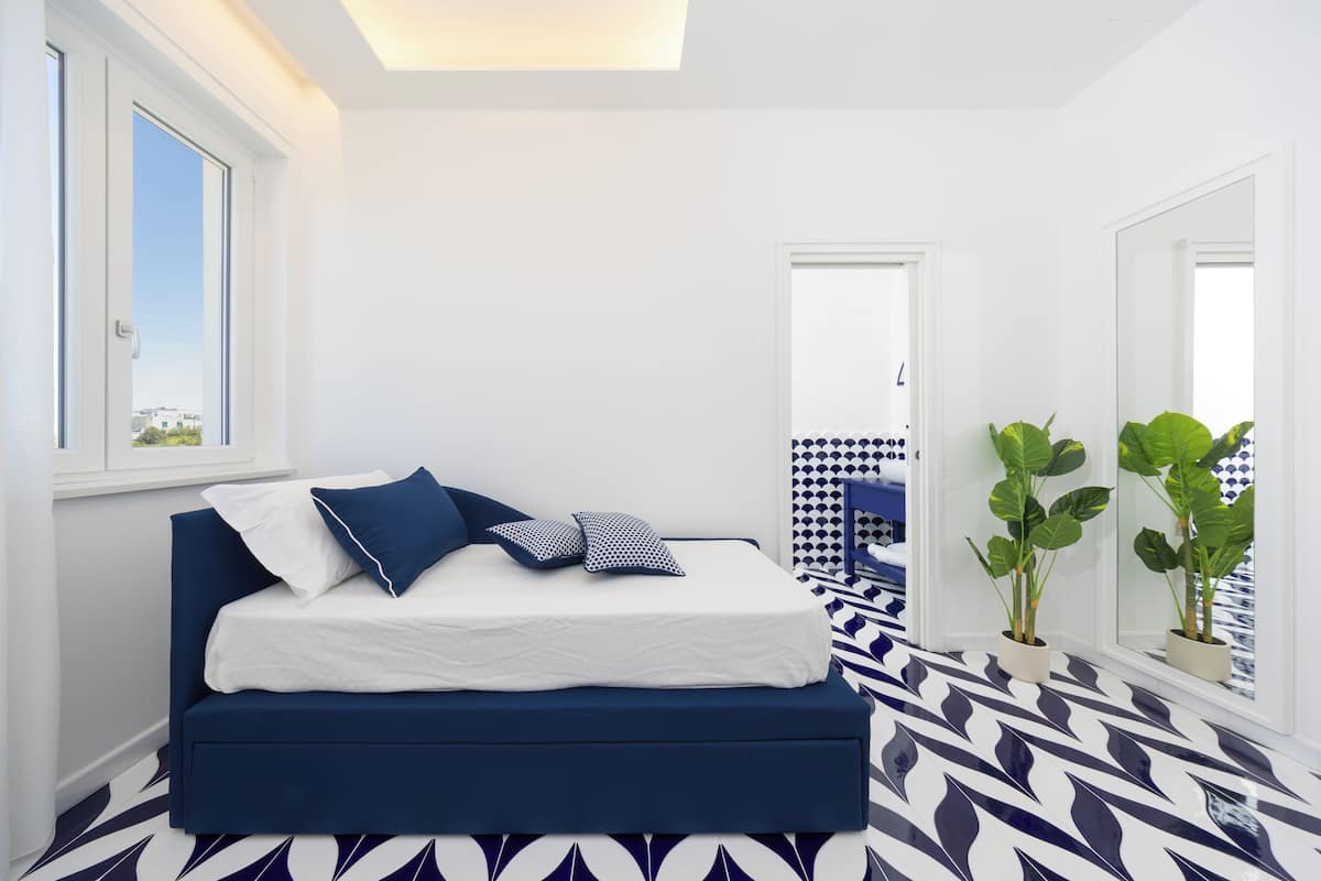 A bedroom with a bed, a window, and a patterned floor.
