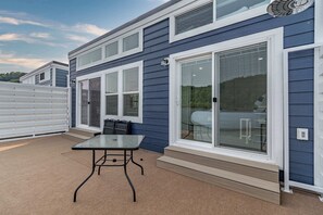 A modern building with large windows, a covered patio with a table, and a garage door.