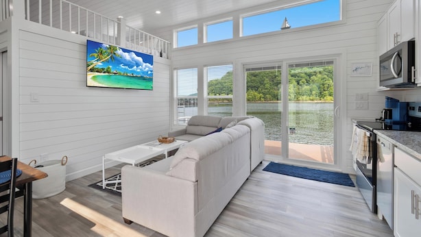 A modern kitchen with white cabinetry, a microwave, and a stove. - De La Float - Floating House on Lake Cumberland (Russell Springs)