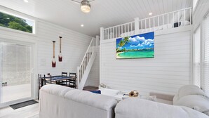 A spacious living area with a white sofa, a dining table with chairs, a staircase, and a large window. - De La Float - Floating House on Lake Cumberland (Russell Springs)