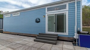 Un edificio blu con un'ampia finestra, gradini che conducono all'ingresso e un piccolo faretto esterno.