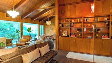 Un vaste espace de vie doté d’un plafond en bois, d’une bibliothèque intégrée et d’un canapé.