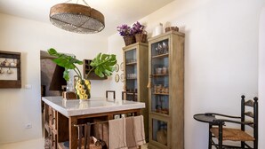 A dining area with a wooden table, a cabinet with glass doors, and a hanging light fixture. - Villa 'Trulli San Domenico' with Private Pool, Wi-Fi and Air Conditioning (Martina Franca)