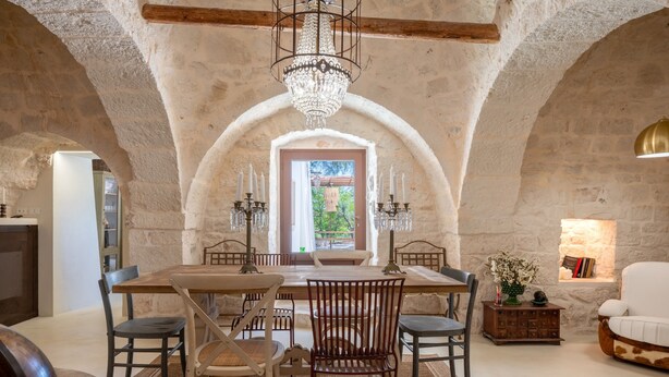 A dining area with a high arched ceiling, a chandelier, and a view through a window. - Villa 'Trulli San Domenico' with Private Pool, Wi-Fi and Air Conditioning (Martina Franca)