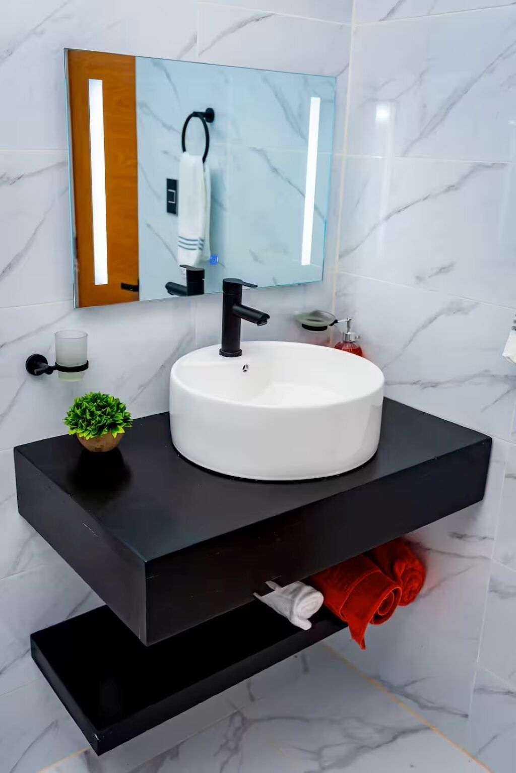 A bathroom with a white sink, black countertop, and a mirror above.
