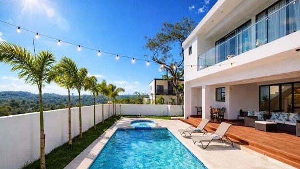 A modern pool area with a clear view of the surrounding landscape, a wooden deck, and a white building with large windows. - Spacious Luxury Villa - Pool, Jacuzzi & View. (Camu)
