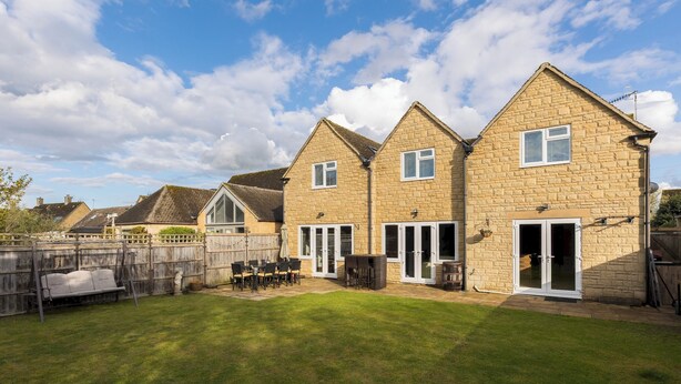 A residential property with a backyard patio, a wooden fence, and a brick house with a pitched roof. - Central Bourton Gem|5 Bedrooms|Garden|Parking - Pass the Keys (Bourton-on-the-Water)