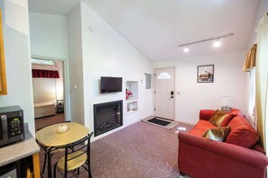 Un espacio habitable compacto con comedor, chimenea, televisor y sofá.
